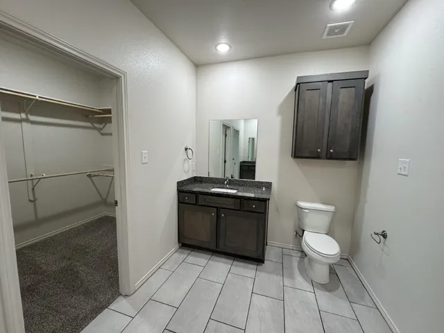 a spacious bathroom with a toilet a sink and a mirror