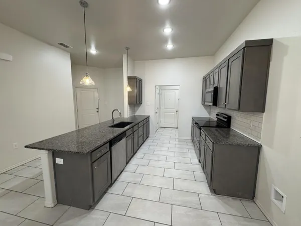 a hallway with granite countertop a sink a counter top space and stainless steel appliances