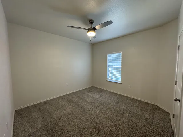 an empty room with a ceiling fan and window
