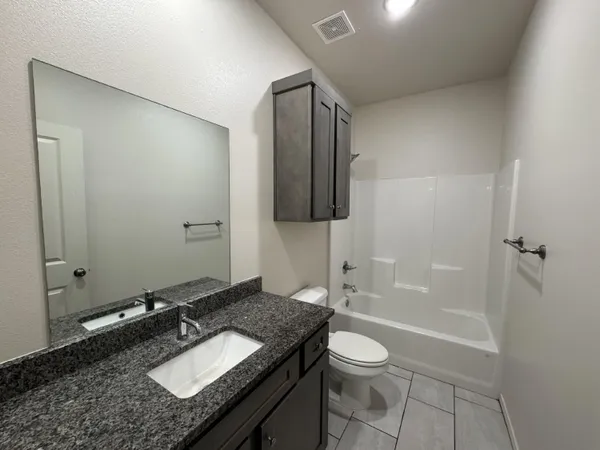 a bathroom with a granite countertop sink toilet and shower