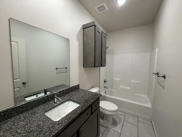 a bathroom with a granite countertop sink toilet and shower