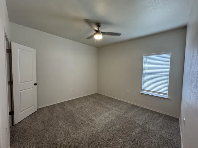an empty room with a fan & a window