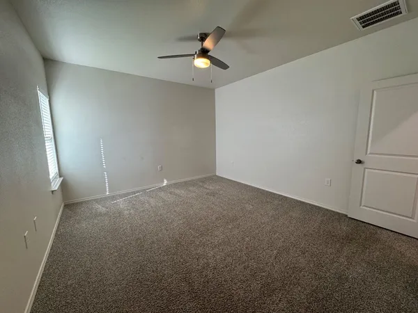 an empty room with ceiling fan and window