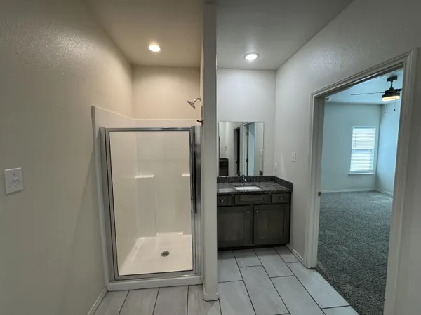 a bathroom with a granite countertop sink a mirror and a shower