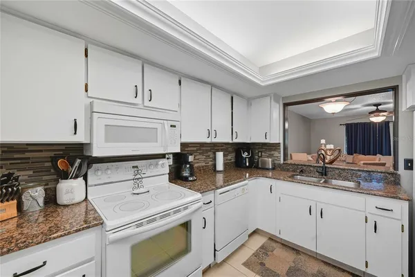 a kitchen with granite countertop a sink stainless steel appliances and white cabinets