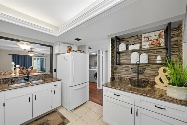 a white kitchen with granite countertop a sink and white cabinets