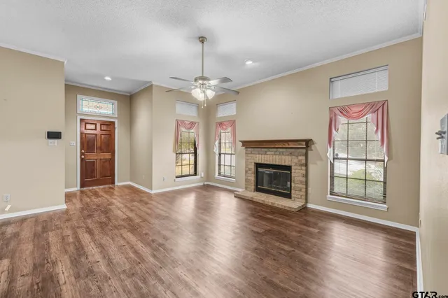 a view of an empty room with wooden floor fireplace and a window