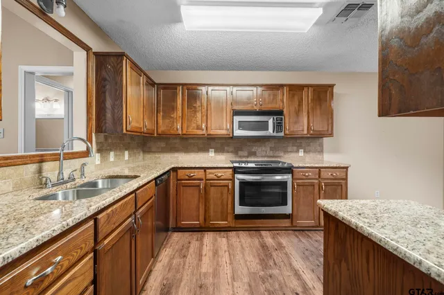 a kitchen with stainless steel appliances granite countertop a sink stove microwave and cabinets