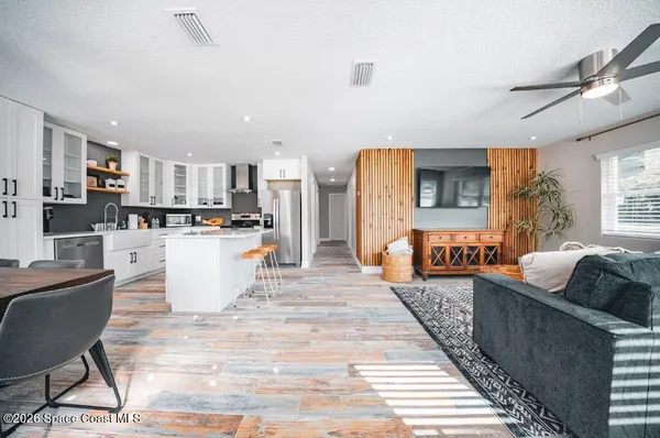 a living room with furniture and a dining table with kitchen appliances