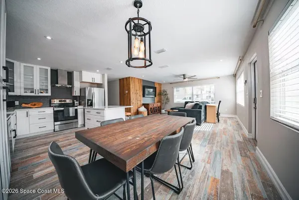 a dining room with wooden floor a chandelier a wooden table and chairs