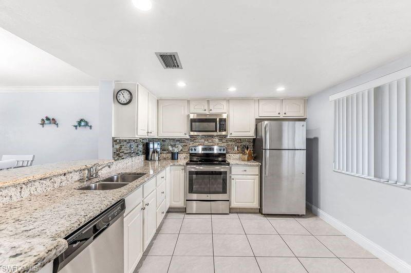5841 Rattlesnake Hamm Road, Unit I101 Naples, FL 34113 - Photo 1 of 17 Kitchen with tile backsplash, sink, light colored granite countertops, light tile patterned flooring, and stainless steel appliances