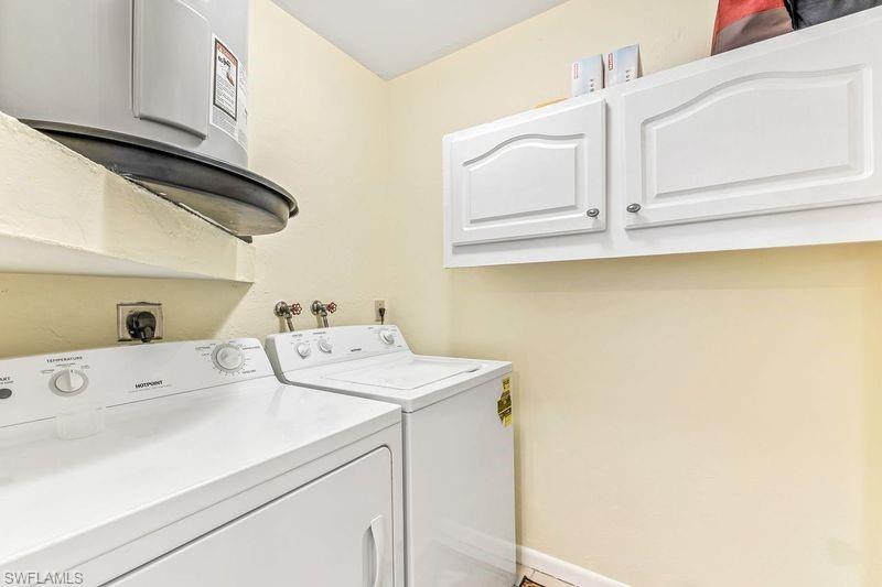 5841 Rattlesnake Hamm Road, Unit I101 Naples, FL 34113 - Photo 12 of 17 In unit laundry/storage area with cabinets, water heater, and washer and dryer