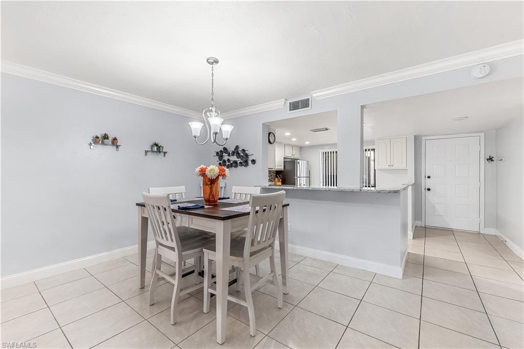 5841 Rattlesnake Hamm Road, Unit I101 Naples, FL 34113 - Photo 4 of 17 Tiled dining space featuring crown molding and a chandelier and countertop area for bar stools