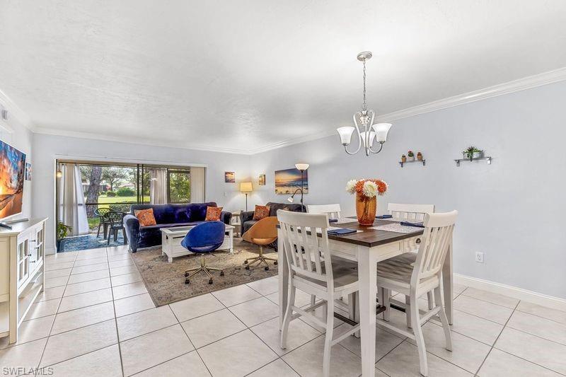 5841 Rattlesnake Hamm Road, Unit I101 Naples, FL 34113 - Photo 5 of 17 Dining/Living space featuring light tile patterned flooring, ornamental molding, and a chandelier