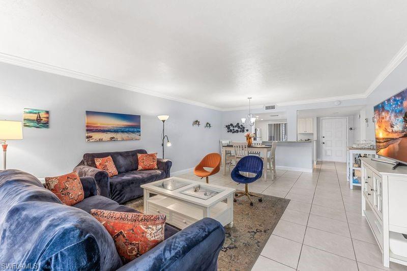 5841 Rattlesnake Hamm Road, Unit I101 Naples, FL 34113 - Photo 7 of 17 Living room featuring a chandelier, crown molding, and light tile patterned flooring