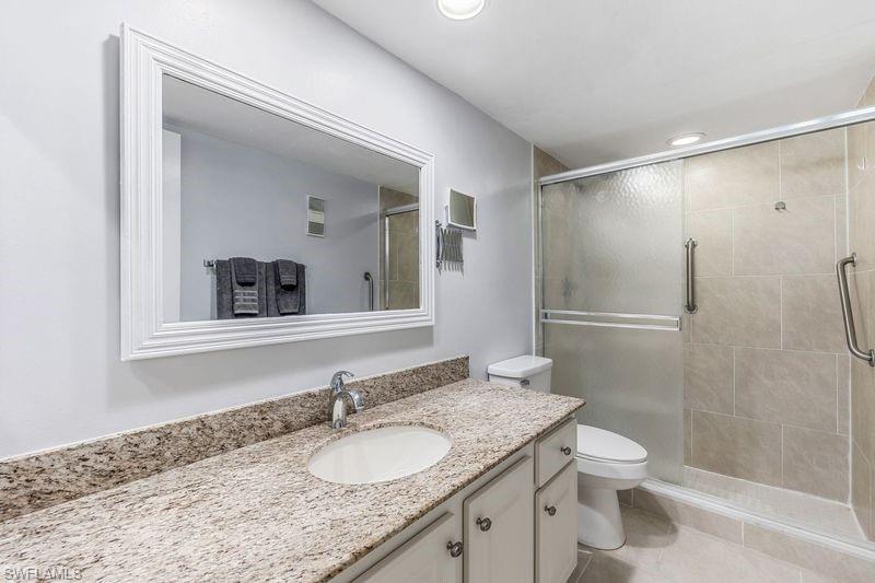 5841 Rattlesnake Hamm Road, Unit I101 Naples, FL 34113 - Photo 9 of 17 Master bathroom featuring tile patterned flooring, vanity, toilet, and a tiled shower with glass door