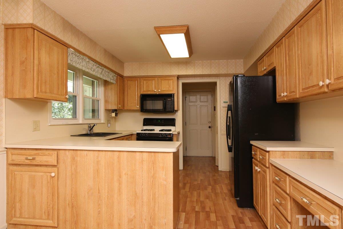 4508 Oak Park Road Raleigh, NC 27612 - Photo 5 of 24 a kitchen with stainless steel appliances granite countertop a refrigerator a stove top oven a sink and dishwasher with wooden floor