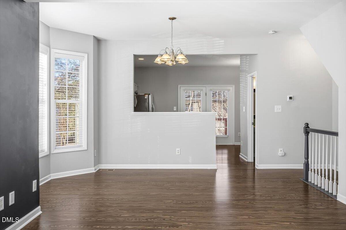 5531 Crabtree Park Court Raleigh, NC 27612 - Photo 6 of 41 an empty room with wooden floor chandelier and windows