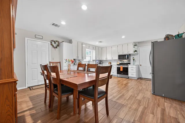 a kitchen with granite countertop wooden floors stainless steel appliances and sink