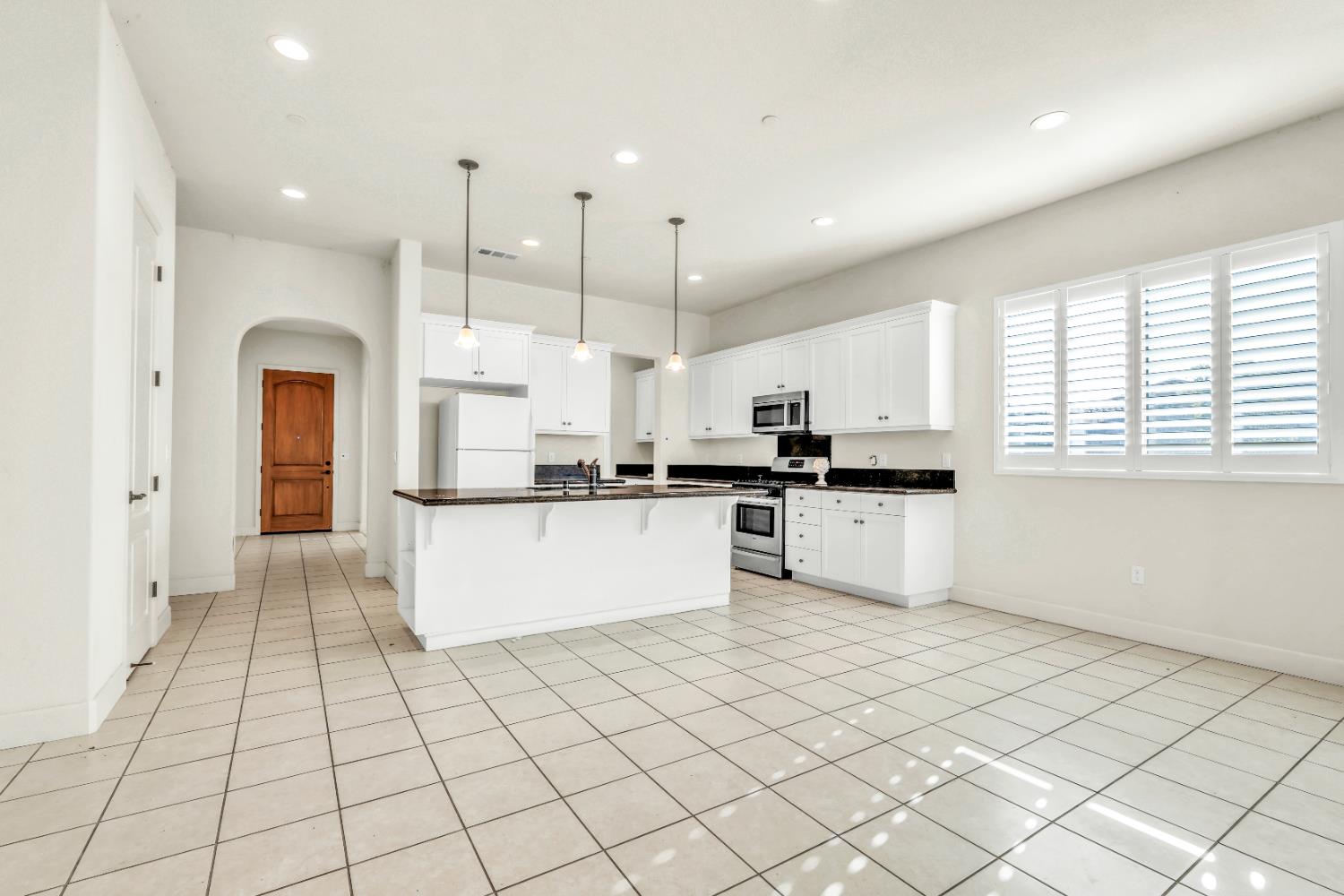 4129 Castellina Way Manteca, CA 95337 - Photo 25 of 58 a kitchen with stainless steel appliances kitchen island granite countertop a refrigerator a sink and white cabinets