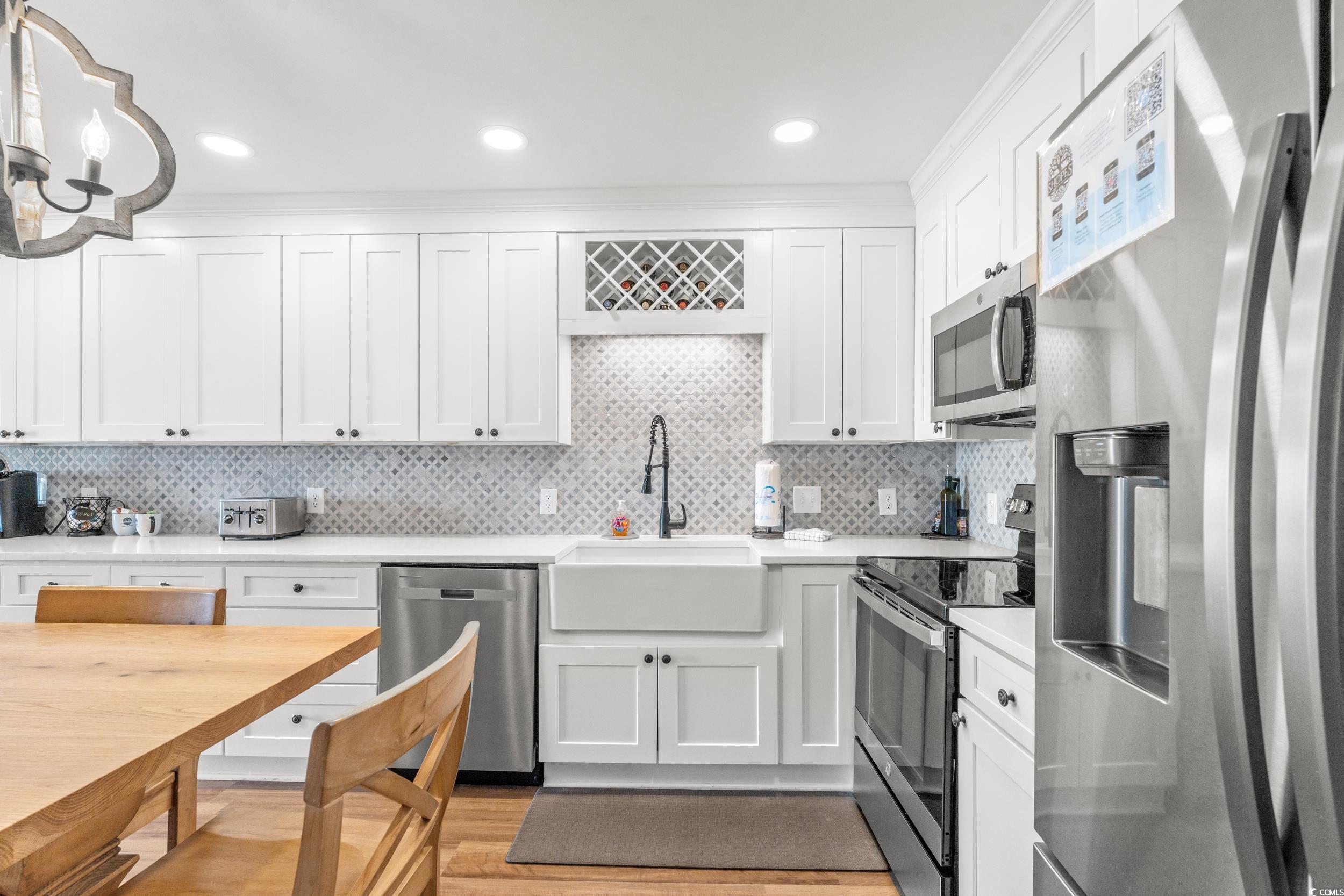 917 Ocean Boulevard South, Unit 304 Surfside Beach, SC 29575 - Photo 13 of 38 Kitchen featuring stainless steel appliances, white cabinetry, decorative backsplash, light wood finished floors, and light stone counters