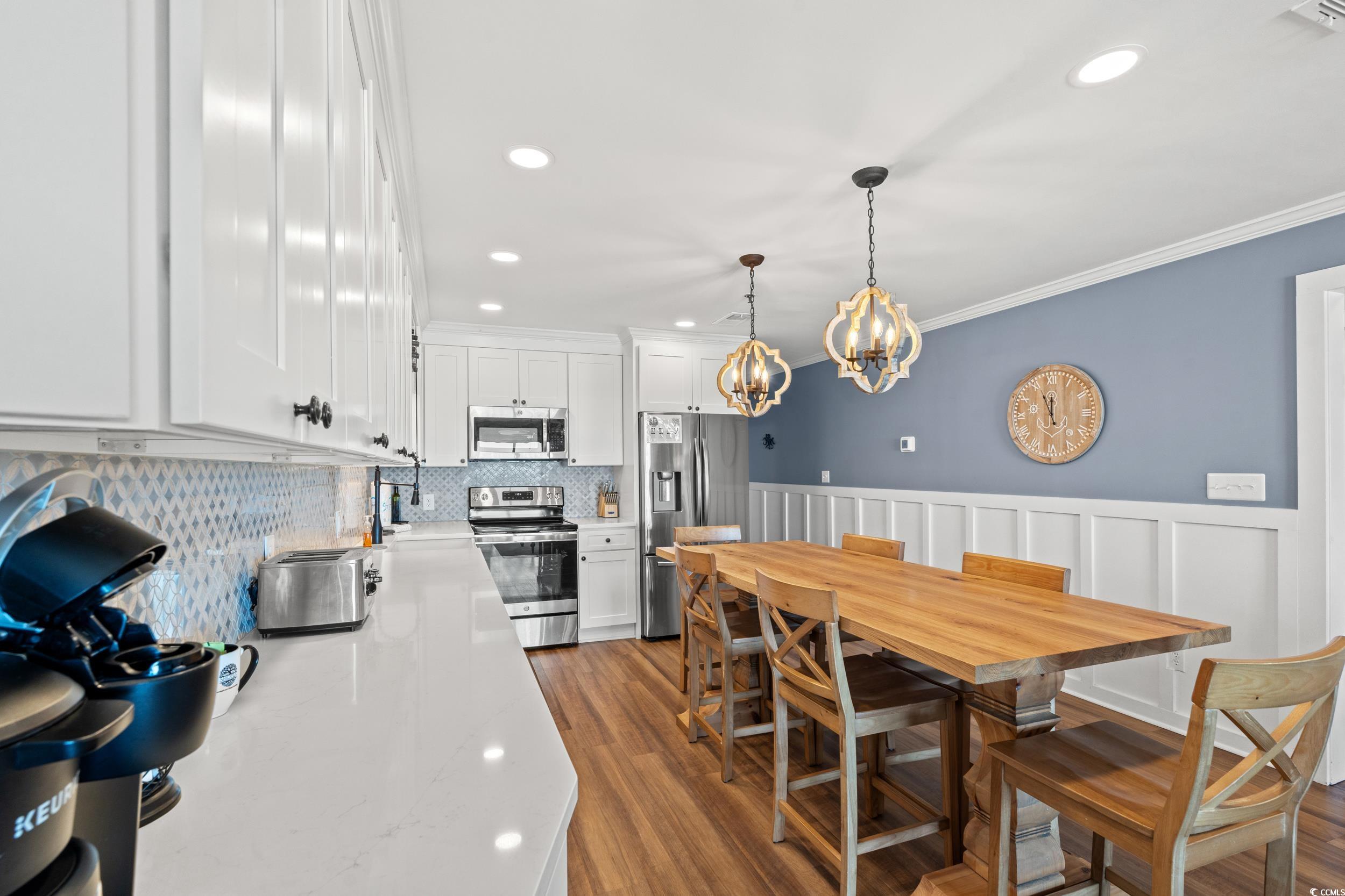 917 Ocean Boulevard South, Unit 304 Surfside Beach, SC 29575 - Photo 14 of 38 Dining area featuring wainscoting, dark wood-style floors, recessed lighting, a decorative wall, and crown molding