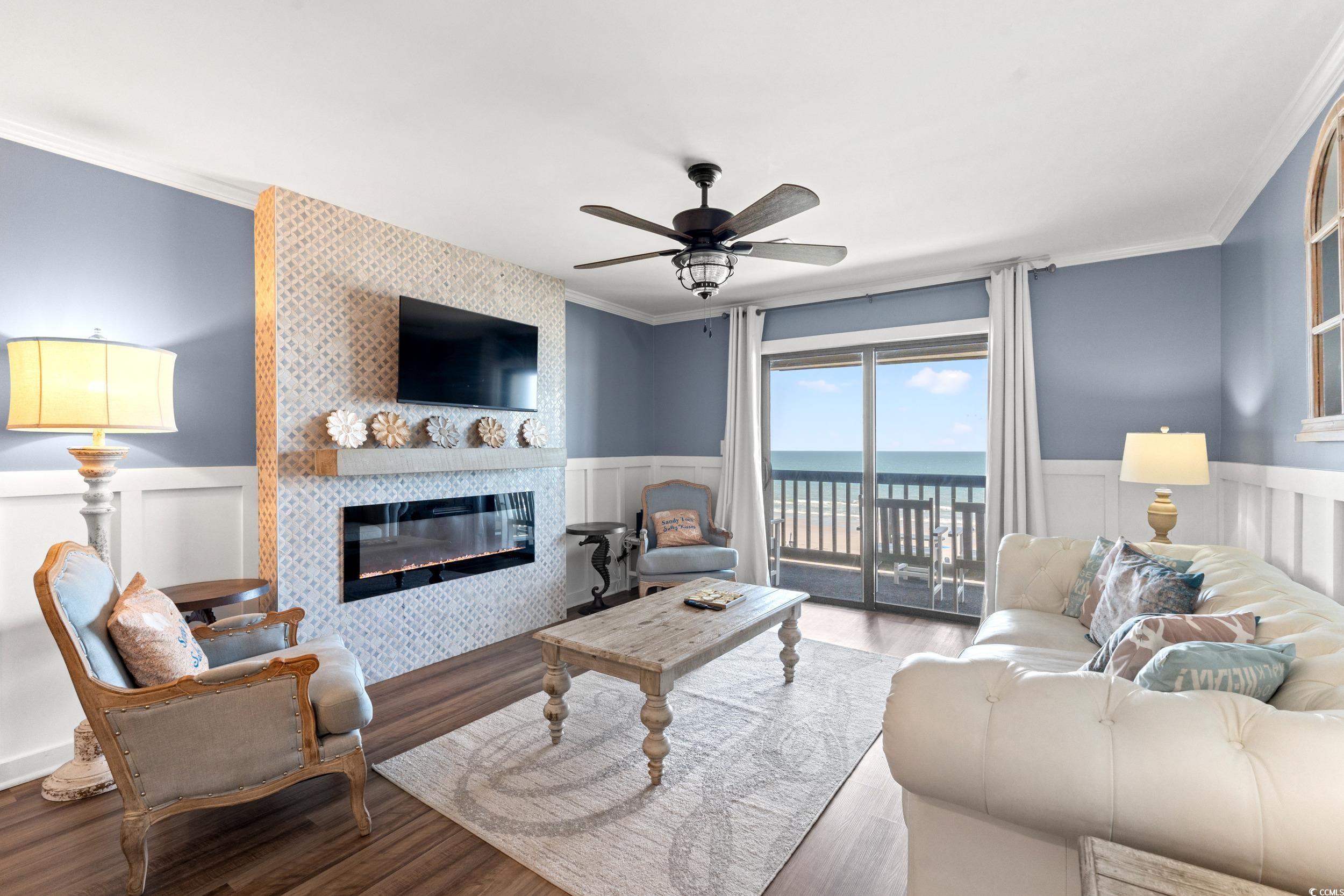 917 Ocean Boulevard South, Unit 304 Surfside Beach, SC 29575 - Photo 7 of 38 Living area with wainscoting, ornamental molding, a tile fireplace, wood finished floors, and a decorative wall