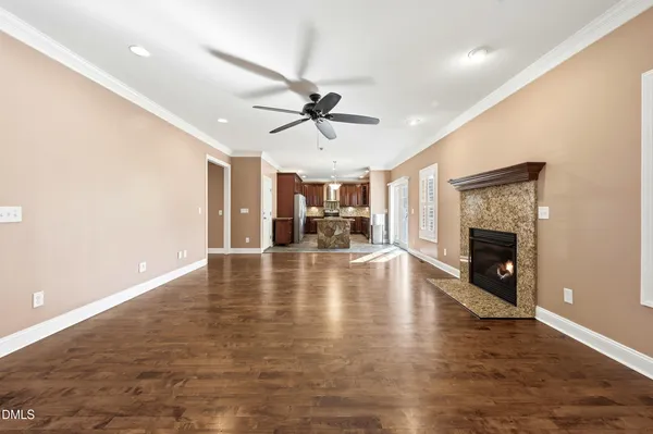 an empty room with wooden floor a ceiling fan a fireplace and windows