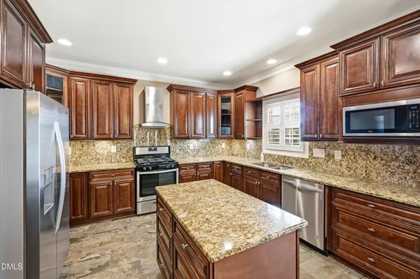 a kitchen with stainless steel appliances granite countertop a refrigerator a sink and a stove