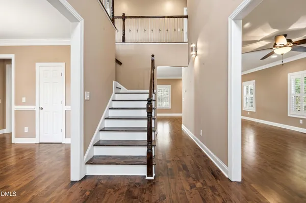 a view of staircase with lots of frames on wall and wooden floor