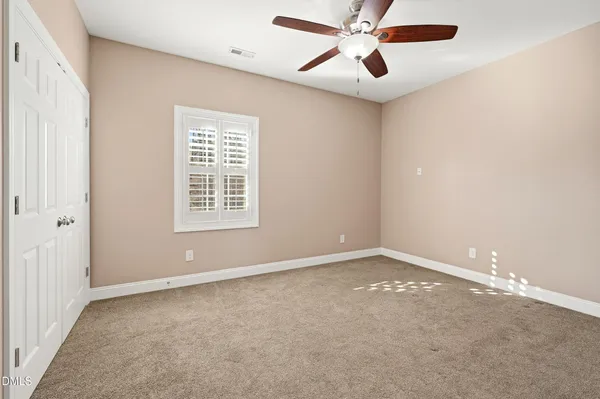 an empty room with windows and fan