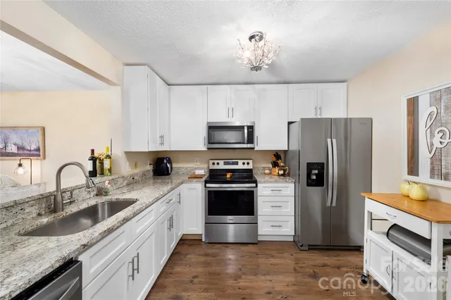 a kitchen with granite countertop a sink stove and refrigerator