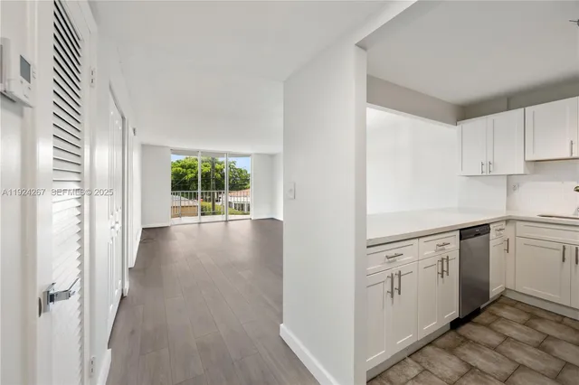 a view of a kitchen with white cabinets and wooden floor