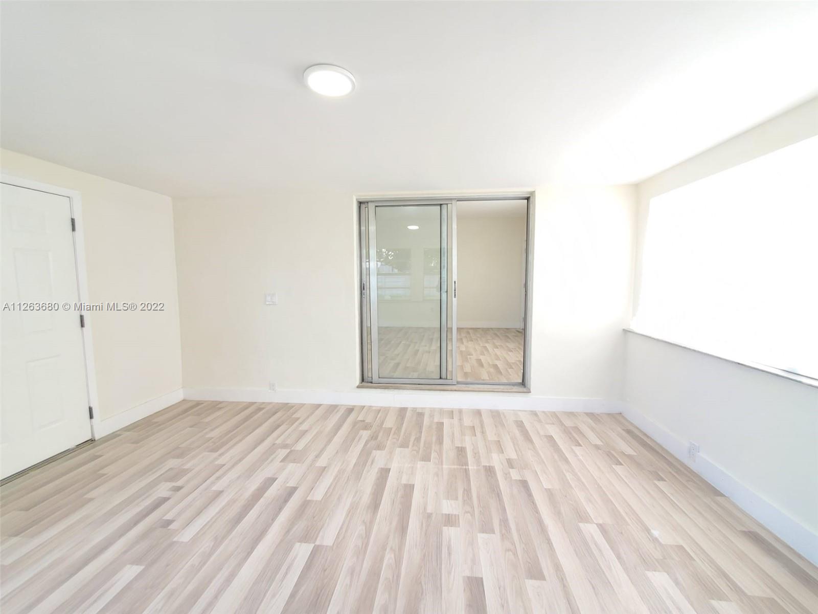 291 West 41st Street Hialeah, FL 33012 - Photo 34 of 40 an empty room with wooden floor and windows