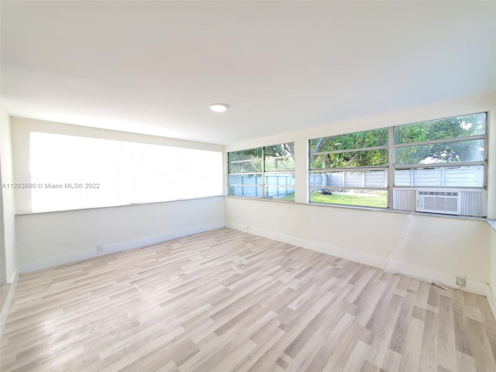 291 West 41st Street Hialeah, FL 33012 - Photo 6 of 40 an empty room with wooden floor and windows