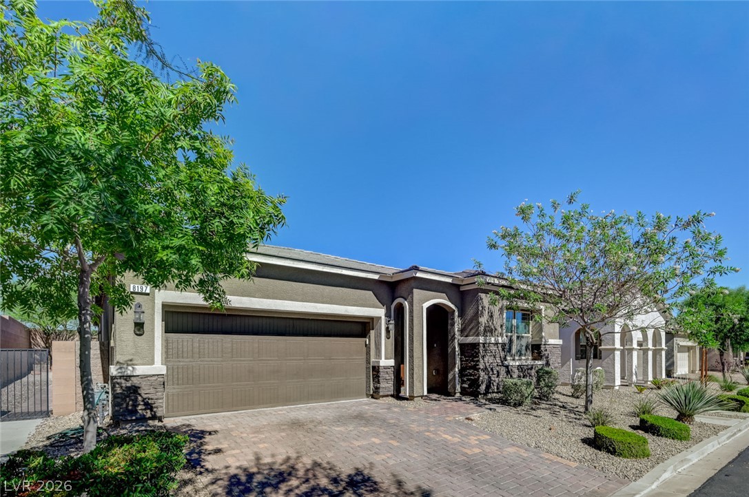 8197 Riley Love Street Las Vegas, NV 89139 - Photo 3 of 48 A welcoming facade showcases stone accents and a brick paver driveway leading to the integrated garage.