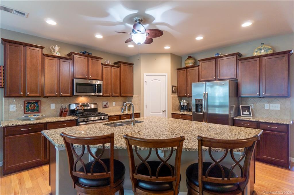 4051 Perth Road Indian Land, SC 29707 - Photo 5 of 31 a kitchen with stainless steel appliances granite countertop a dining table chairs refrigerator and cabinets