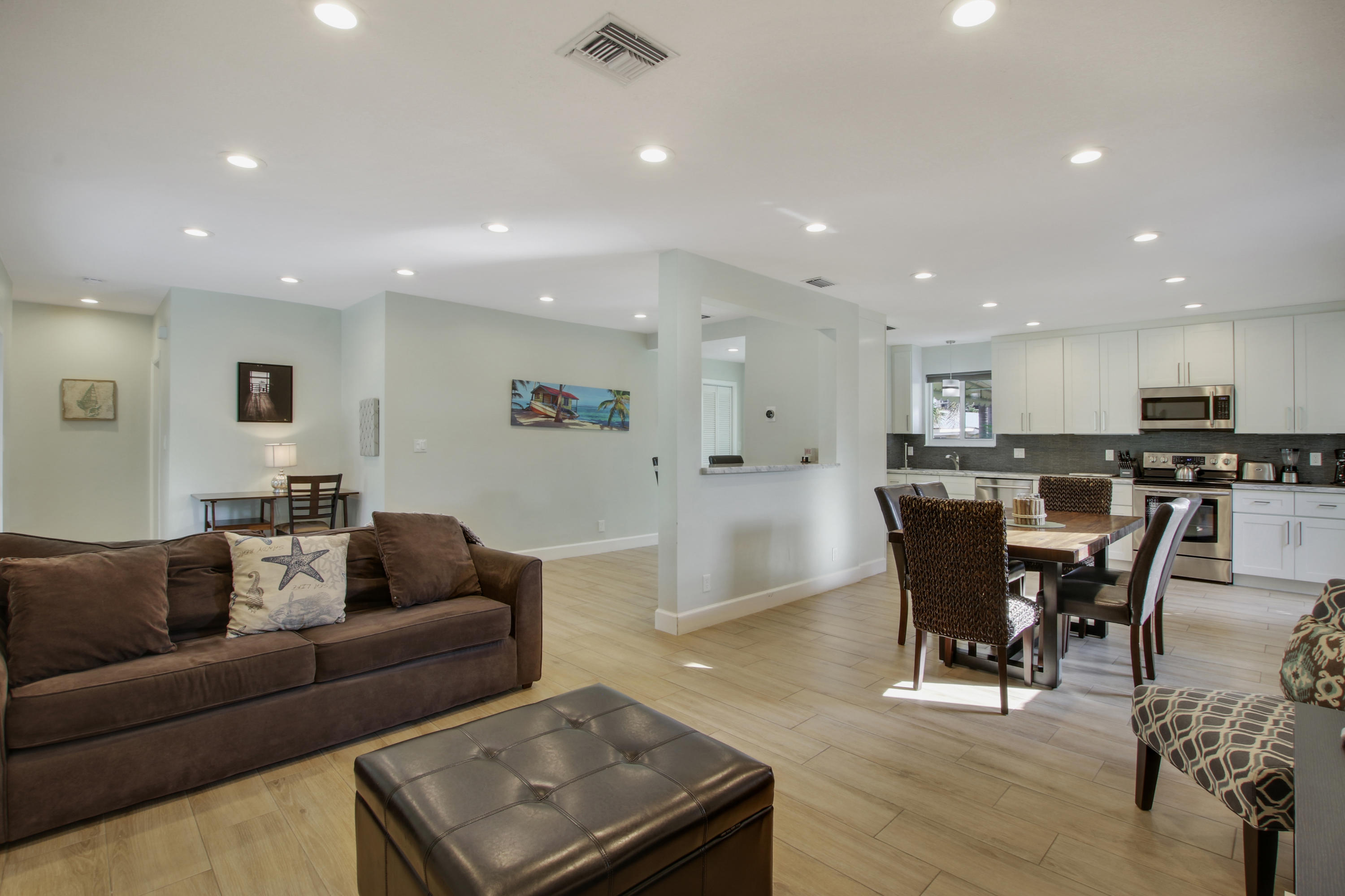 380 North Juno Lane Juno Beach, FL 33408 - Photo 3 of 22 a living room kitchen with a dining table wooden floor and a view of kitchen