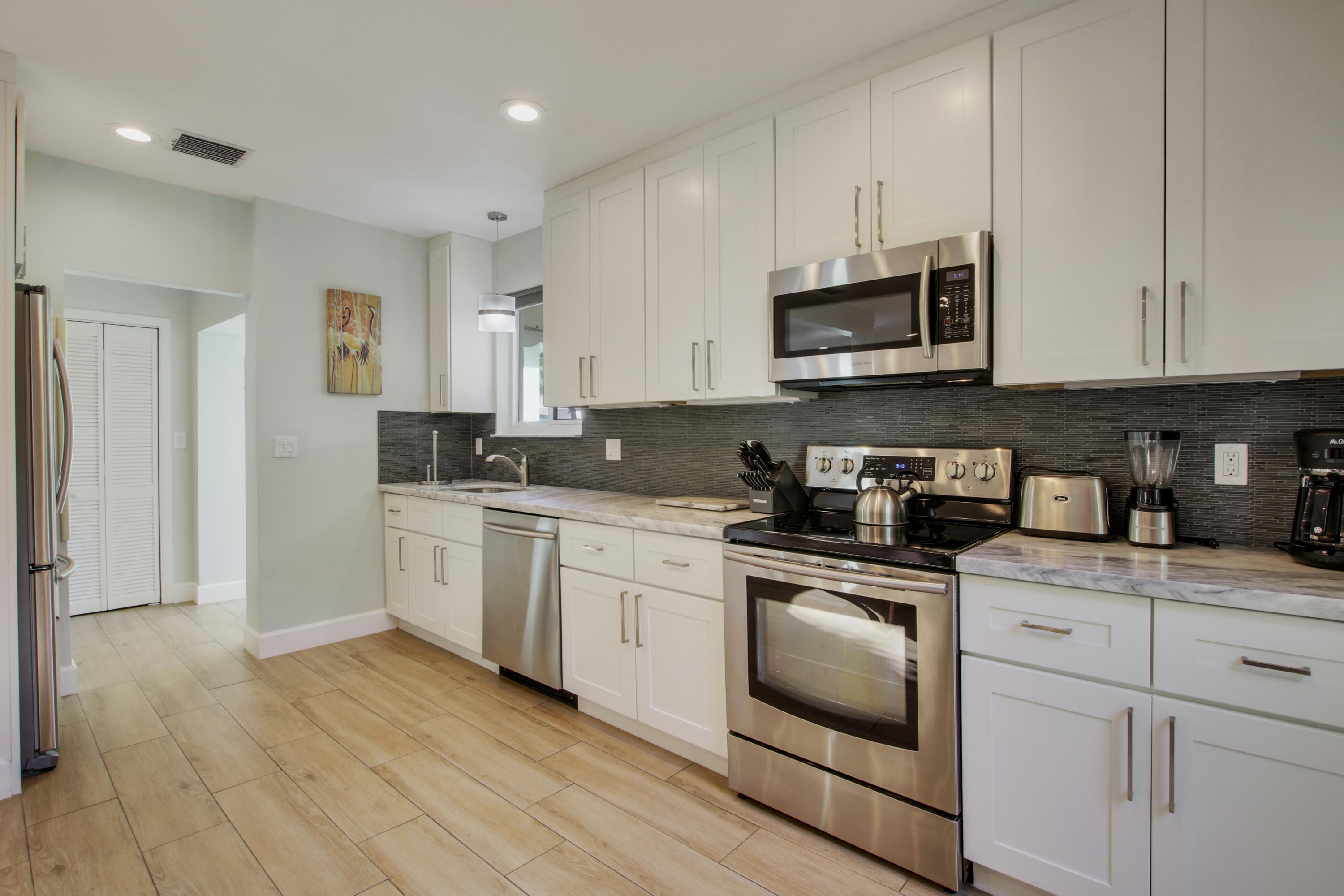 380 North Juno Lane Juno Beach, FL 33408 - Photo 4 of 22 a kitchen with granite countertop white cabinets and white appliances