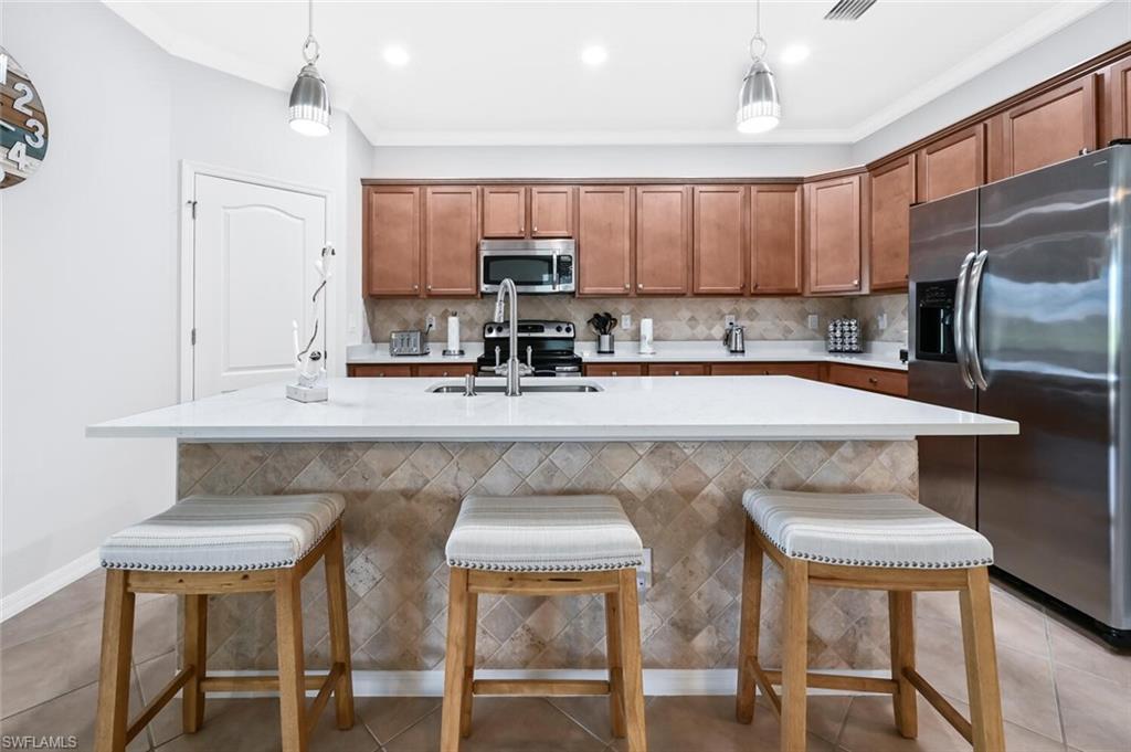 3742 Treasure Cove Circle Naples, FL 34114 - Photo 7 of 22 a kitchen with stainless steel appliances granite countertop a sink and chairs