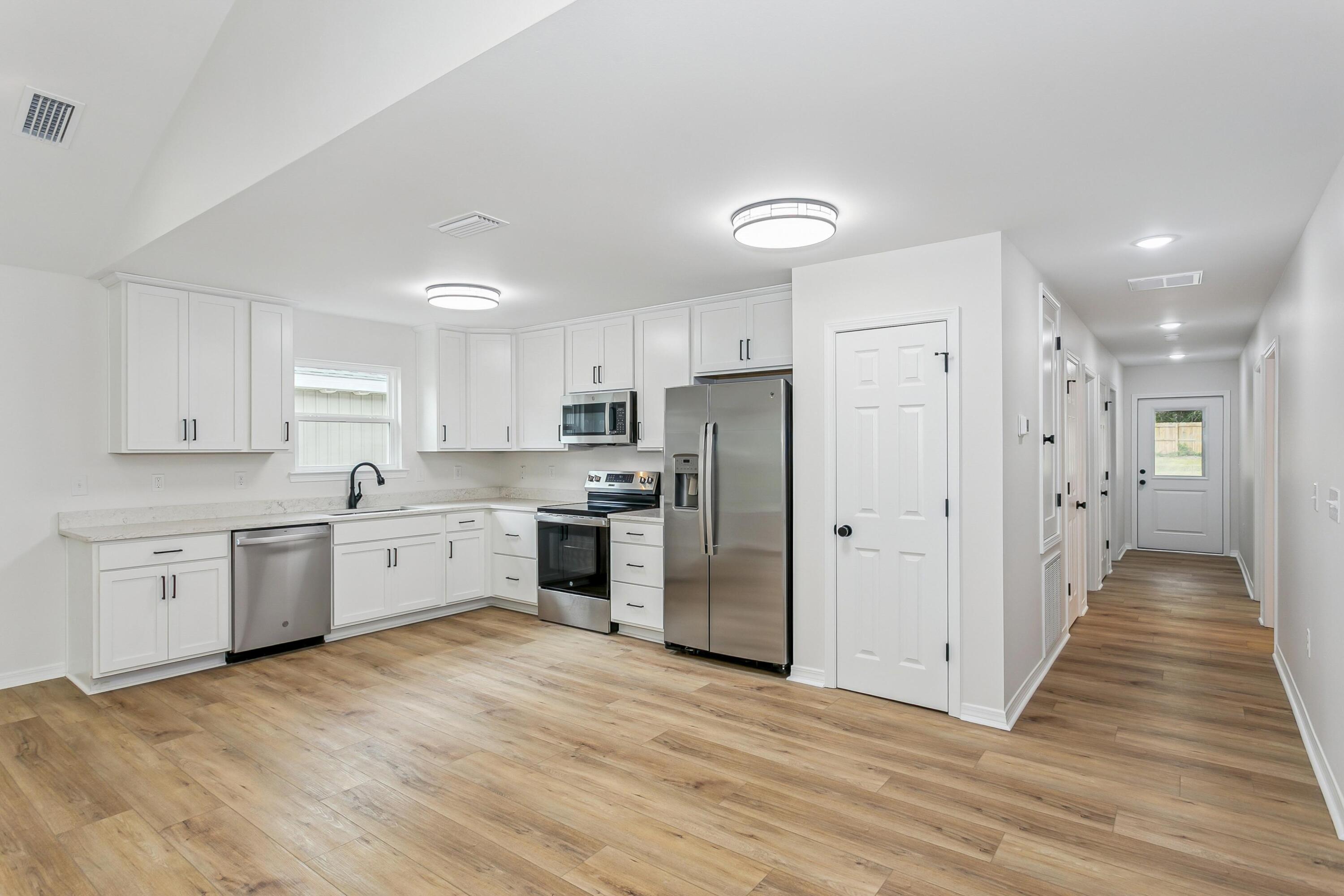 8086 3rd Street Laurel Hill, FL 32567 - Photo 16 of 35 a large kitchen with cabinets and wooden floor