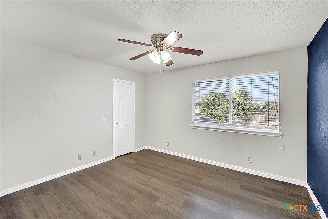 113 Endeavour Kyle, TX 78640 - Photo 25 of 38 an empty room with wooden floor ceiling fan and windows