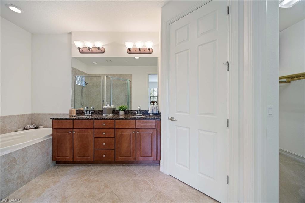 9134 Chula Vista Street, Unit 125 Naples, FL 34113 - Photo 15 of 44 a spacious bathroom with a bathtub sink and mirror