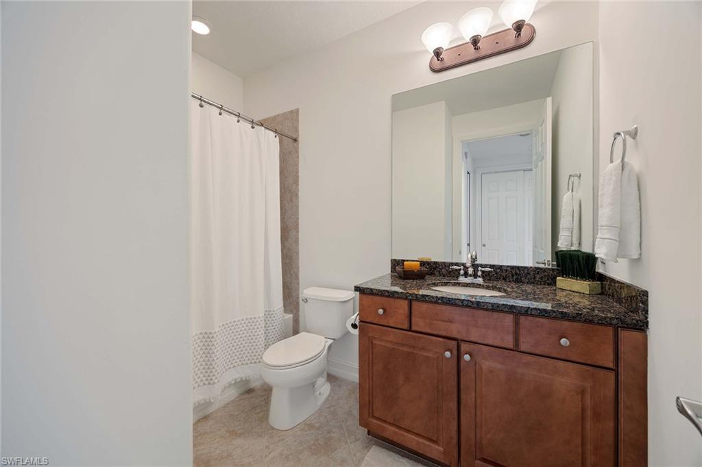 9134 Chula Vista Street, Unit 125 Naples, FL 34113 - Photo 20 of 44 a bathroom with a granite countertop sink a toilet and a mirror