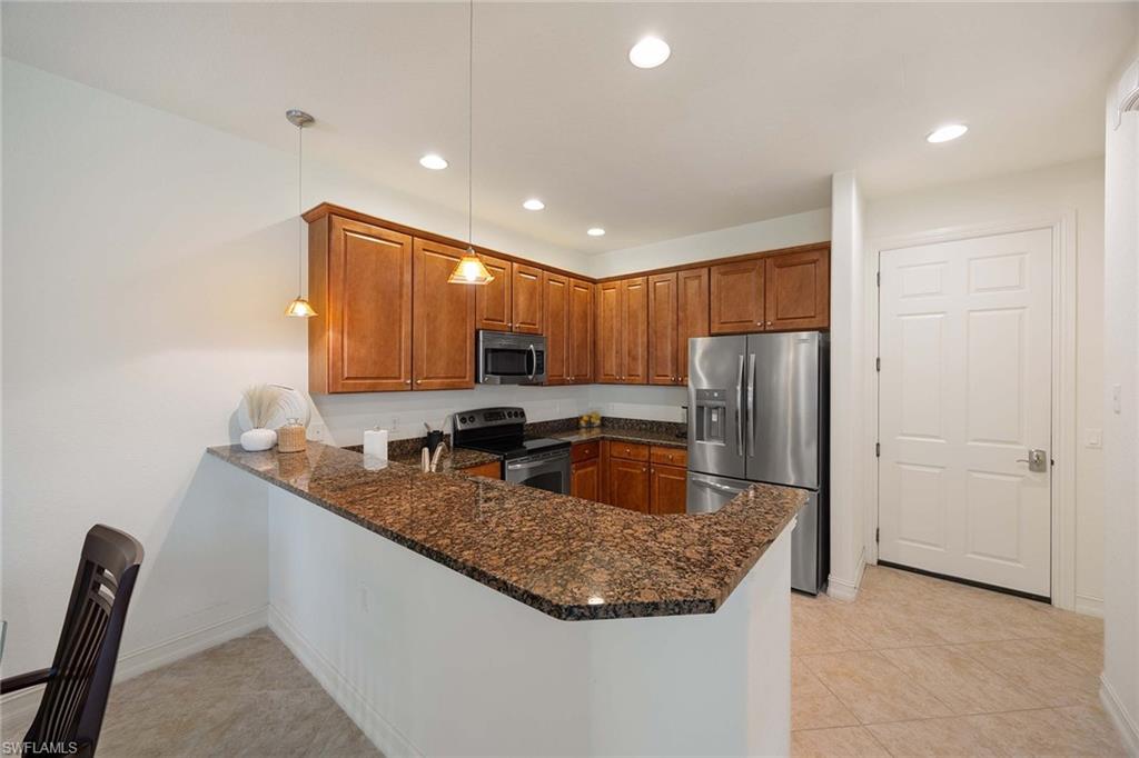 9134 Chula Vista Street, Unit 125 Naples, FL 34113 - Photo 5 of 44 a kitchen with stainless steel appliances granite countertop a sink a refrigerator and a stove