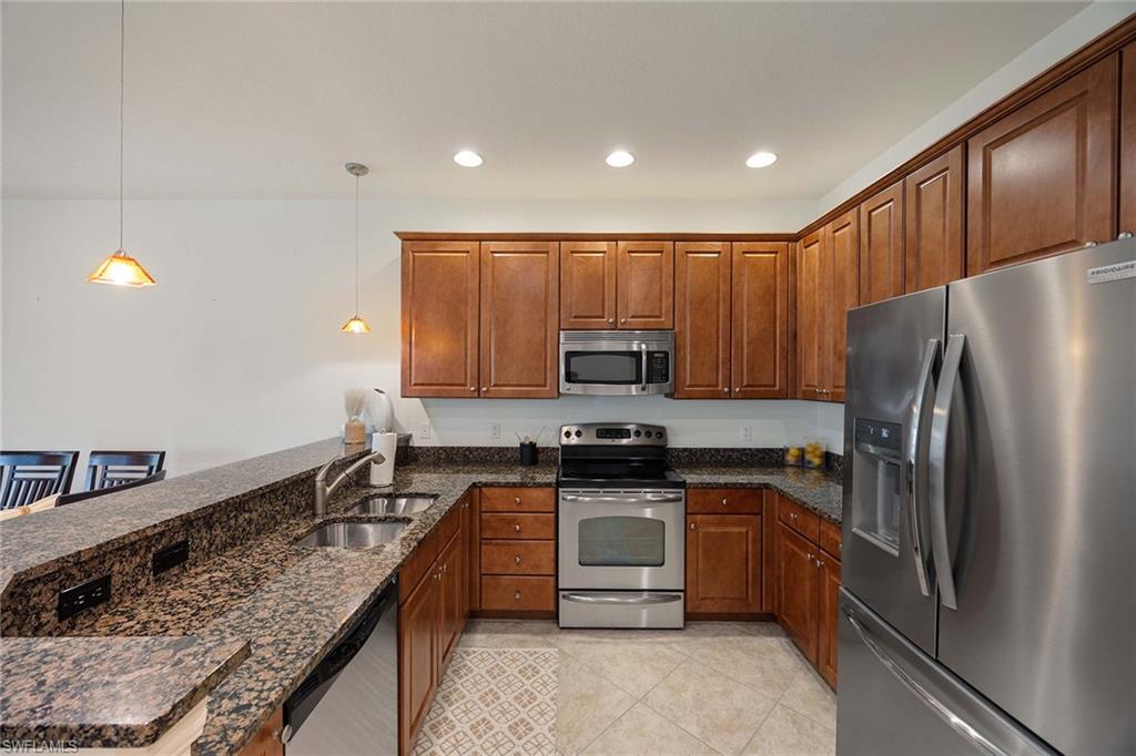 9134 Chula Vista Street, Unit 125 Naples, FL 34113 - Photo 6 of 44 a kitchen with stainless steel appliances granite countertop a stove a sink and a refrigerator