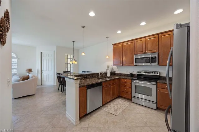 a kitchen with stainless steel appliances granite countertop a stove top oven a sink dishwasher a refrigerator and white cabinets with wooden floor