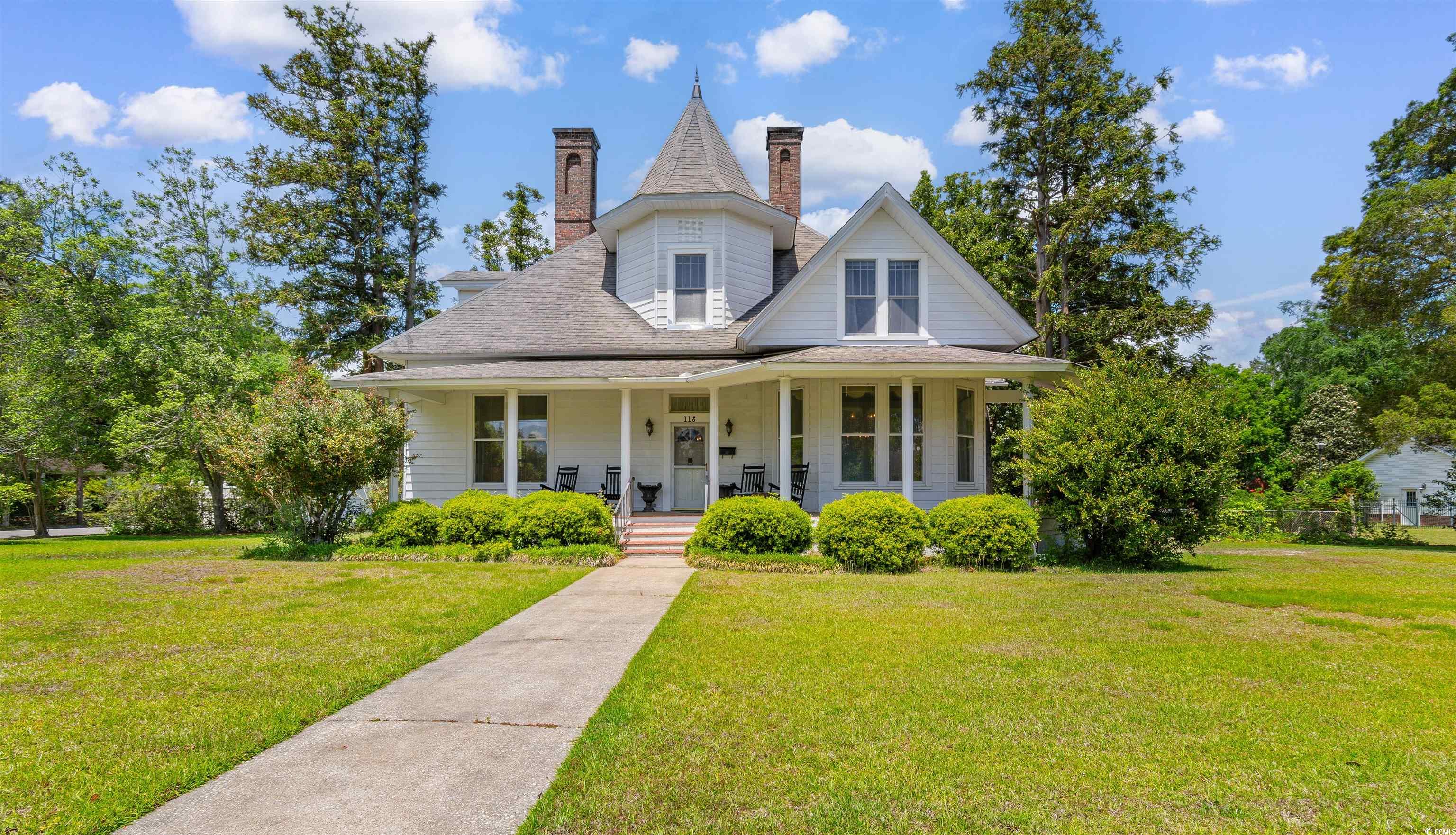 Victorian house with a porch, a front lawn, and a chimney