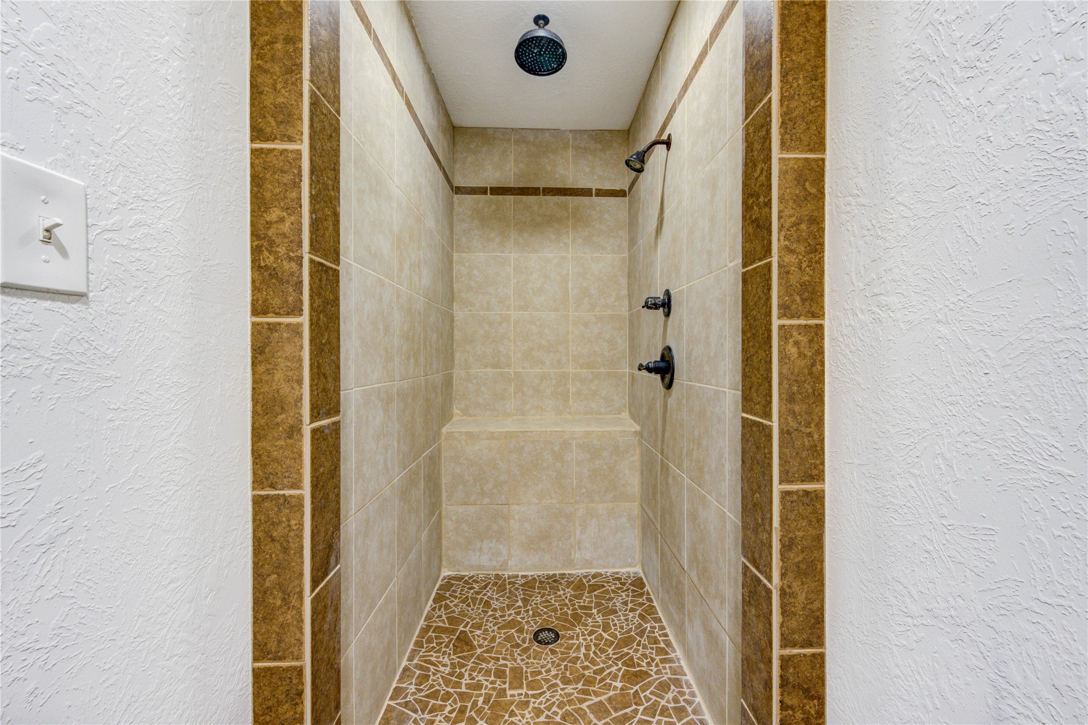 8805 Sun Oil Road Brenham, TX 77833 - Photo 38 of 50 Spacious walk-in shower featuring elegant tile work, dual showerheads, and a built-in bench for added comfort and luxury.