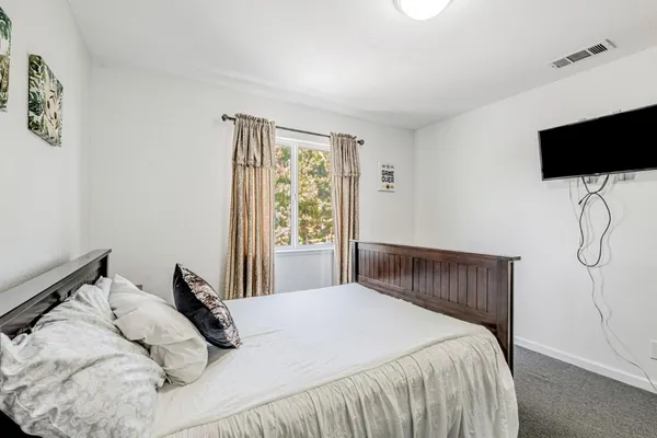 a bedroom with a bed tv and a window